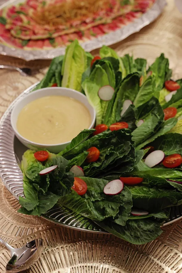 Romaine, cherry tomatoes and radishes with a bowl of dressing