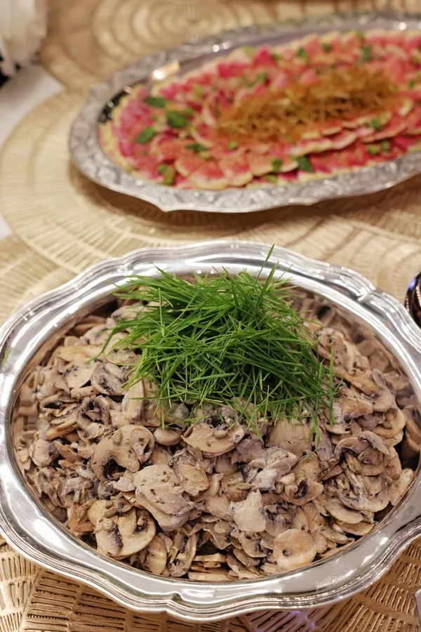 Sautéed mushrooms topped with dill, with beef carpaccio behind
