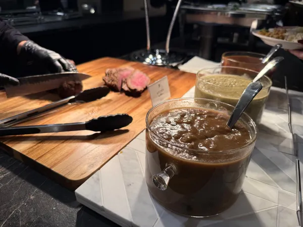 Roast beef being carved beside a bowl of house-made sauce